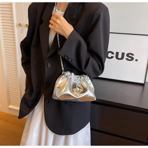 Detail of silver metallic cloud bag with pleats, metal chain and pearl pendant charm