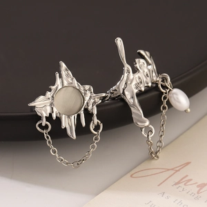 Close-up of silver fluid ring set with cat-eye stone, metal chain and hanging pearl detail