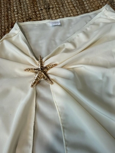 Détail d'un haut de bikini avec ornement étoile de mer dorée sur un tapis de paille