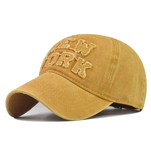 Close-up of mustard cotton baseball cap with embroidered New York letters and frayed edges
