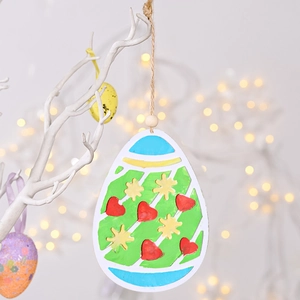 Detail of wooden Easter egg pendant with heart patterns hanging on a white branch