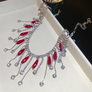 Detailed close-up of a silver vintage necklace with red crystal tassels on velvet