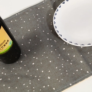 Gray Christmas table runner with white polka dots and rustic linen texture on dining table