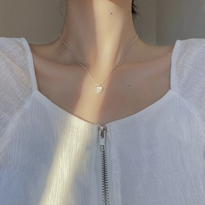 Close-up of 925 silver shell heart necklace on collarbone with elegant natural lighting