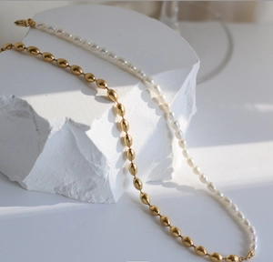 Detail of 18K gold barrel beads and white pearls necklace over white stone