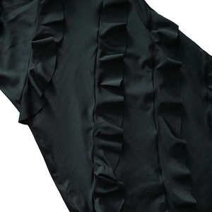 Détail du tissu noir avec volants verticaux et texture lisse avec reflets