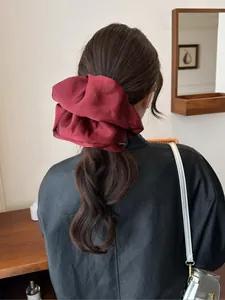 Deep red satin oversized scrunchie styled on a low ponytail with elegant silk texture
