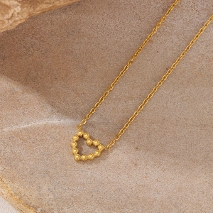 Gros plan d'un collier avec pendentif cœur doré sur un fond en pierre texturée