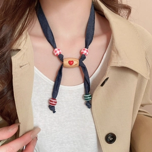 Cute puppy style fabric necklace with wooden beads and red heart pendant on beige coat