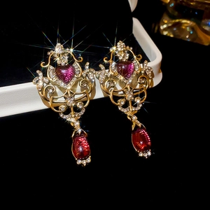 Macro shot of vintage gold earrings with heart-shaped purple gemstones and micro diamonds