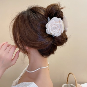 Dettaglio del fermaglio a fiore in raso bianco panna e collana di perle su una modella