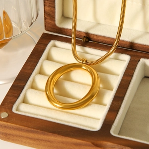 Close-up of gold oval pendant on snake chain inside a wooden jewelry box