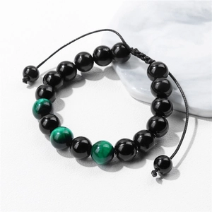 Macro shot of 10mm tiger eye beads and black beads on an adjustable braided bracelet