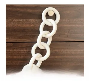 Detail of matte white ceramic chain ring wall hanging decor against a dark wood background