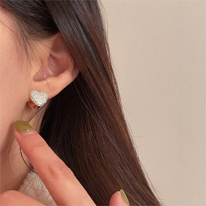 Close-up of minimalist heart stud earrings with sparkling cubic zirconia on ear