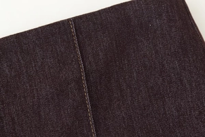 Gros plan détaillé du tissu denim foncé avec surpiqûres jaunes et texture sergé