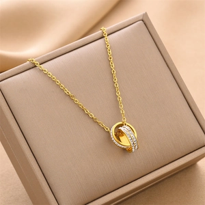 Detailed view of intertwined double ring pendant with white zircons on a beige jewelry box