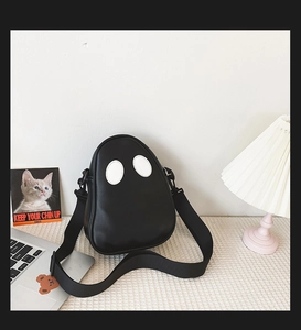 Close-up of ghost-shaped PU leather crossbody bag with white eye patches and nylon strap