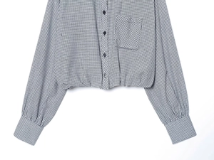 Detail of black and white checkered cropped shirt with buttoned pocket and smooth fabric
