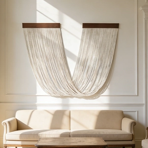 Handwoven macrame wall hanging with wooden poles and elegant fringe tassels in a bright room