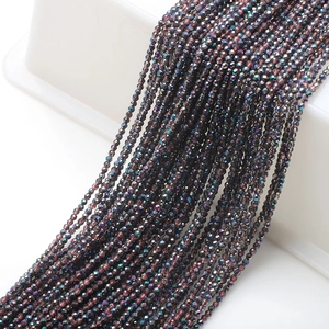 Macro view of 2mm dark iridescent faceted glass beads with AB coating on a white tray