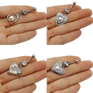 Detailed views of silver heart belly rings with pearls and rhinestones on hands