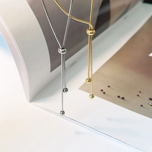 Close-up of adjustable snake chain necklaces in gold and silver finishes on a magazine