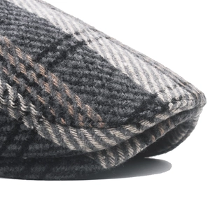 Close-up of thick tweed weave texture and gray plaid pattern on men's winter newsboy cap
