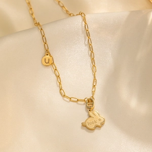 Golden rabbit necklace with luck engraving on beige silk background professional photo