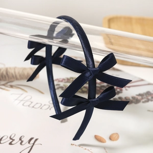 Detailed view of the navy blue satin double bow headband for girls on a glass stand