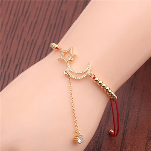 Adjustable gold star and moon bracelet with white cubic zirconia and red cord