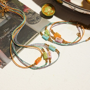 Detail of colorful woven rope bracelets with gold LOVE letter charms and lobster clasps