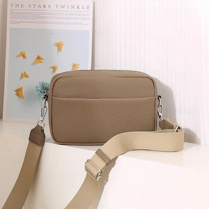 Detail of taupe pebbled leather camera bag with adjustable wide fabric shoulder strap