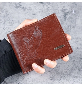 Handheld view of brown pebbled leather men's wallet featuring detailed embossed eagle pattern