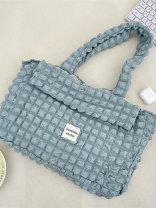 Light blue quilted bubble tote bag with foldover design and spacious interior for commuting