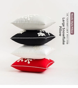 Detail of stacked Christmas snowflake pillows in red, white, black, and gray with embroidery