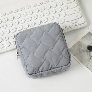 Gros plan d'une trousse de maquillage grise matelassée avec fermeture sur bureau blanc