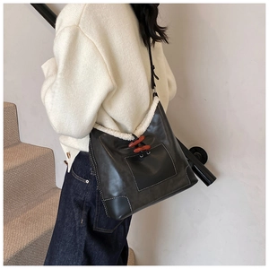 Detail of black tote bag featuring white faux fur trim and a wooden toggle closure