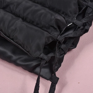 Close-up of black quilted fabric texture and tie-up strap detail of the glossy skirt