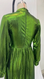 Detail of emerald green pleated fabric with metallic luster on long sleeve maxi dress
