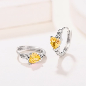 Detail view of heart-shaped yellow gemstone earrings with intricate Celtic knot silver band