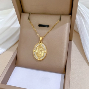 Dettaglio di ciondolo religioso ovale in oro con pavé di cristalli bianchi lucidi