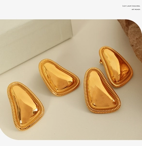 Macro detail of 18K gold-plated geometric earrings with intricate woven texture borders