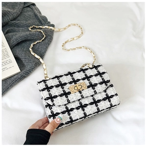 Detail of the black and white tweed texture and gold chain strap on stylish shoulder bag