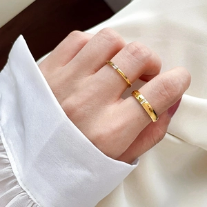Detailed close-up of two gold titanium rings with cubic zirconia worn on hand