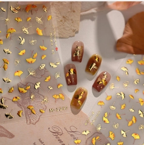 Macro shot of M-1247 gold-edged orange ginkgo leaf nail stickers on warm display