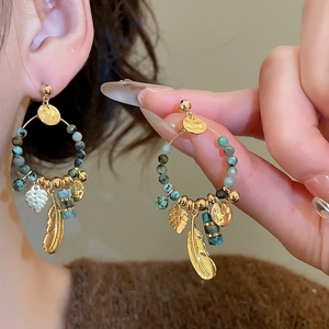 Detailed shot of bohemian gold earrings with turquoise beads and feather leaf pendants