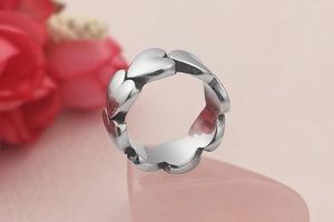 Detailed view of silver heart-shaped intertwined ring on a pink crystal base