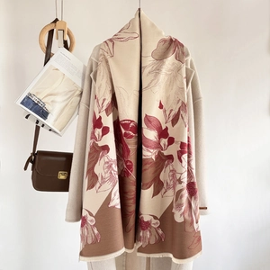 Close-up of thick beige cashmere scarf with elegant floral patterns draped over an overcoat
