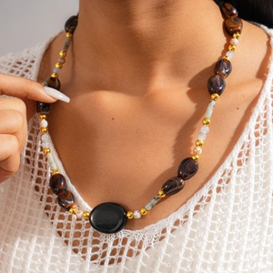 Close-up of bohemian beaded necklace with dark brown beads and oval black stone